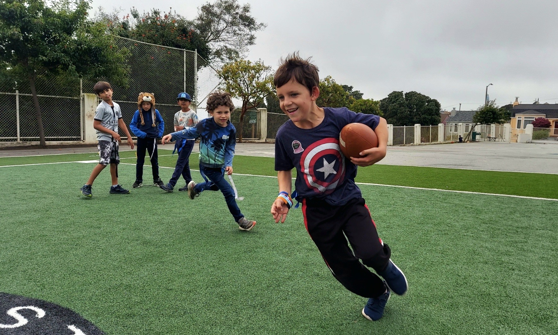 A child running with a football while other children follow.
