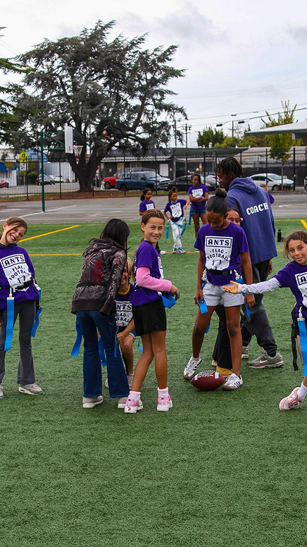 Children and an ANTS coach standing together on a field.