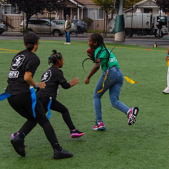 Children playing flag football on a grass field.