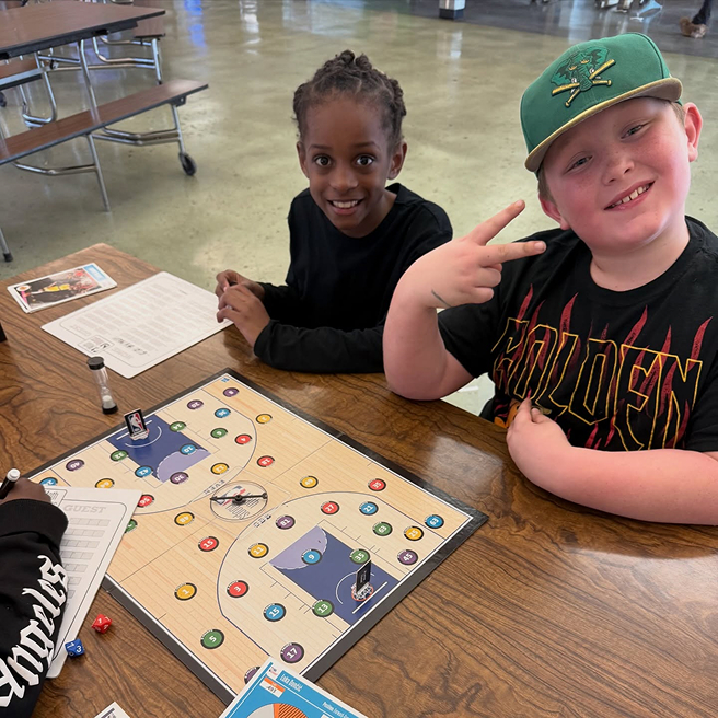 Two children playing a board game at a table.