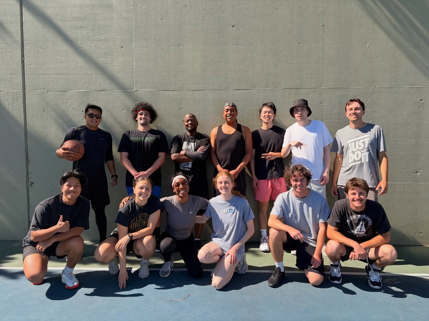 A group posing together with a basketball beside a wall.