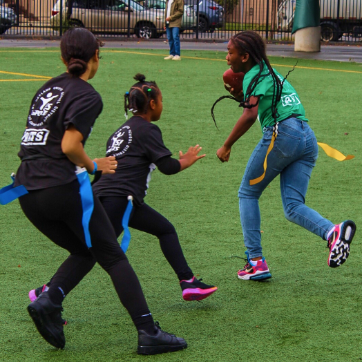 Children playing flag football on a grass field.