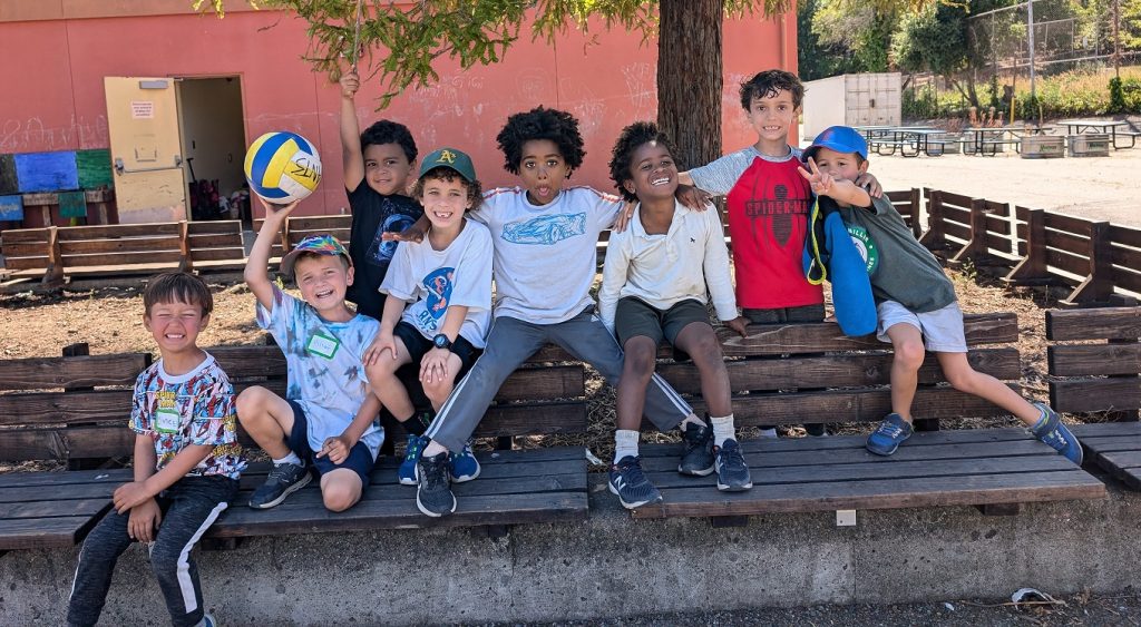 Children sitting together on outdoor steps with sports balls.