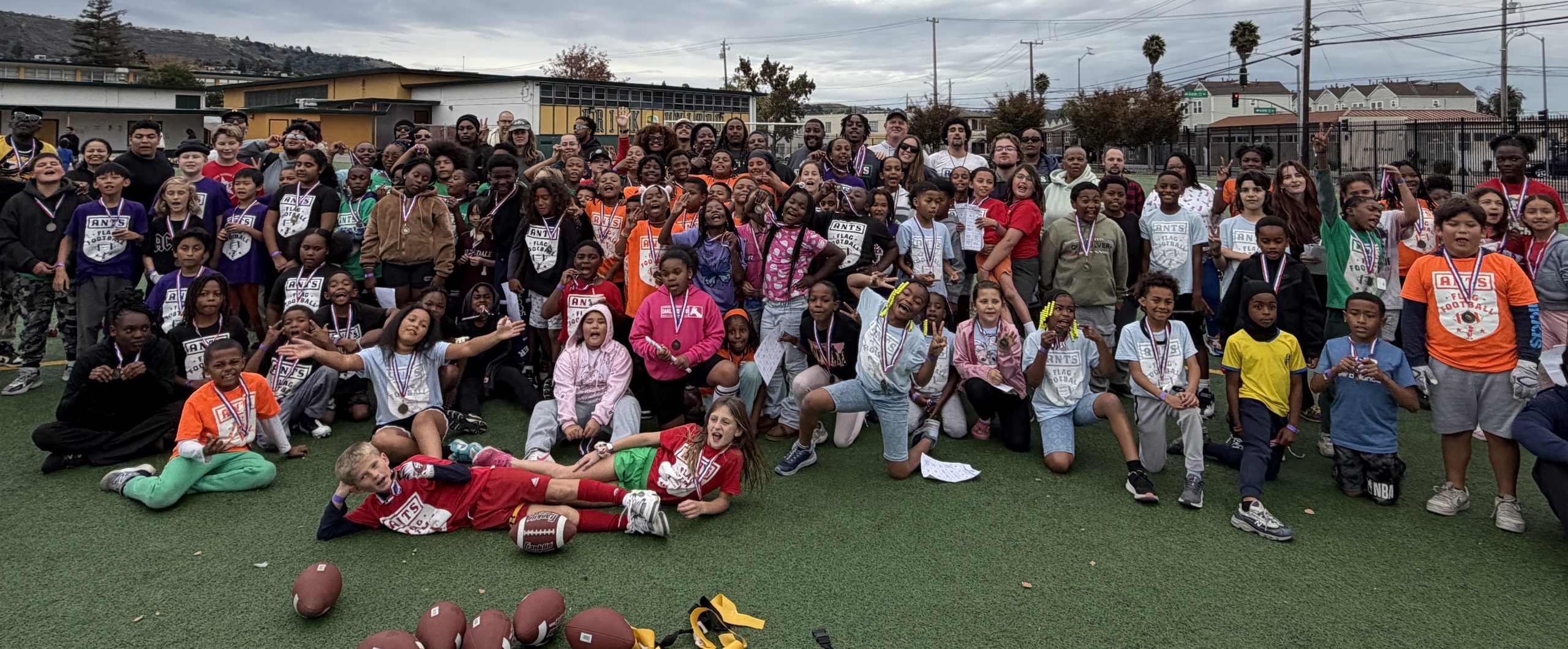 Children, coaches and families gathered on a field for an ANTS flag football event.